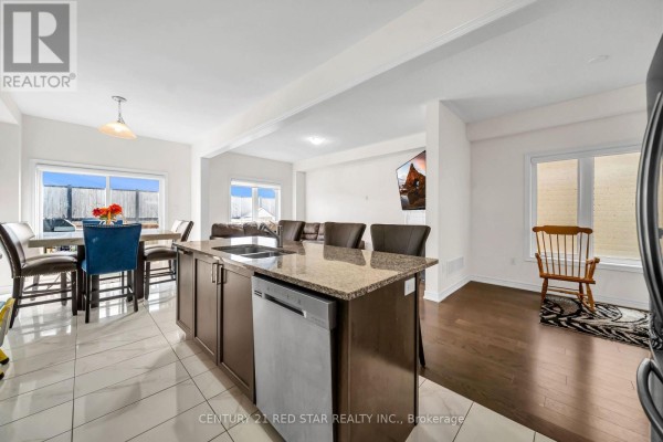 Kitchen island with granite countertops, stainless steel dishwasher, dining table, and open-concept living area - 506 Brooks Street Shelburne