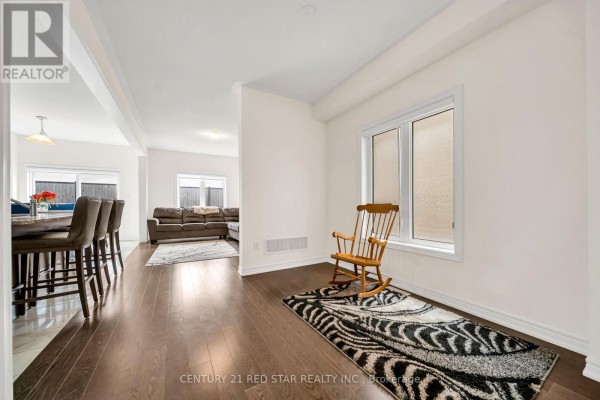 Living room with hardwood floors, rocking chair, zebra rug & view of kitchen island with bar stools - 506 Brooks Street Shelburne