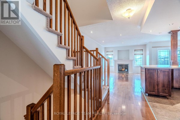Wooden staircase with carpeted steps leading down to a living room with a fireplace. - 506 Pepperville Crescent, Ottawa