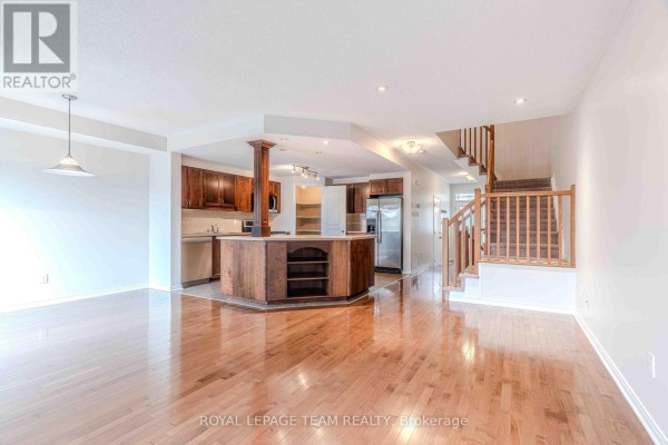 Open concept living area with a kitchen island, dark wood cabinets, and hardwood floors. - 506 Pepperville Crescent, Ottawa