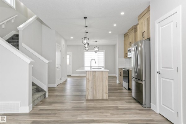 Kitchen with light wood cabinets, stainless steel appliances, island, and pendant lights. - 5060,5062,5064 Chappelle Rd Sw, Edmonton