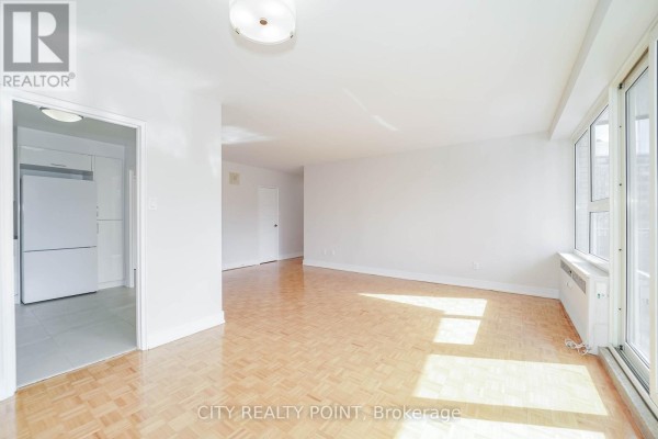 Spacious living area with parquet floors, white walls, and a view of the kitchen. - 507 - 10 Shallmar Boulevard, Toronto