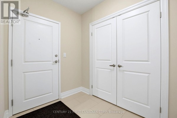 A hallway with two white doors, one to a suite and the other to double closets. - 507 - 260 Villagewalk Boulevard, London North