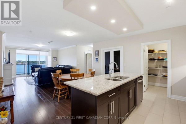 An open concept living space with a kitchen island, dining table, and living room. - 507 - 260 Villagewalk Boulevard, London North