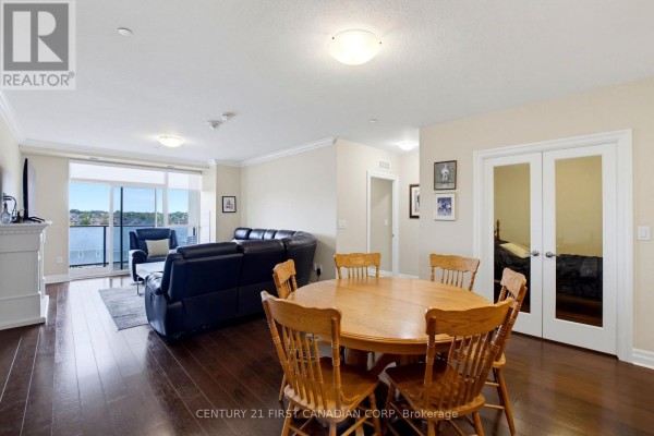 A combined living and dining area with a wooden table, leather sofa, and doorway. - 507 - 260 Villagewalk Boulevard, London North