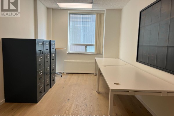 Office room with wood floors, filing cabinets, and white desks, facing a window with blinds. - 507 - 27 Carlton Street, Toronto