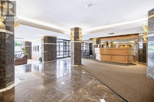 Building lobby with marble floors, decorative columns, a reception desk, and seating area. - 507 - 960 Teron Road, Ottawa