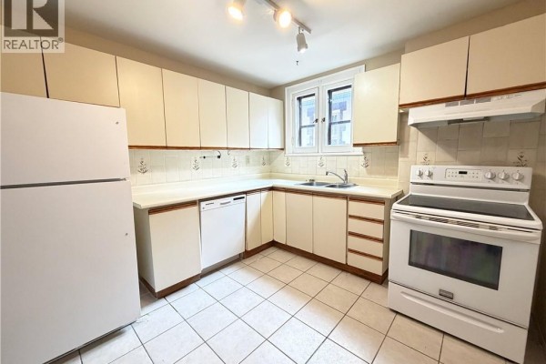 Kitchen with light beige cabinets, white countertops, white appliances, and beige tiled floor. - 507 Aberdeen Avenue, Hamilton