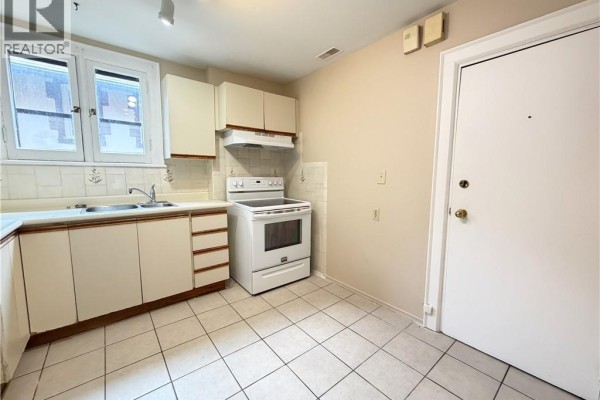 Kitchen corner showing white cabinets, white stove, stainless steel sink, and tiled floor. - 507 Aberdeen Avenue, Hamilton