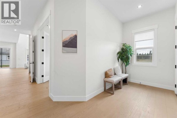Bright entryway with light wood floors, white walls, and a bench near a large window. - 507 Waterford Rise, Chestermere