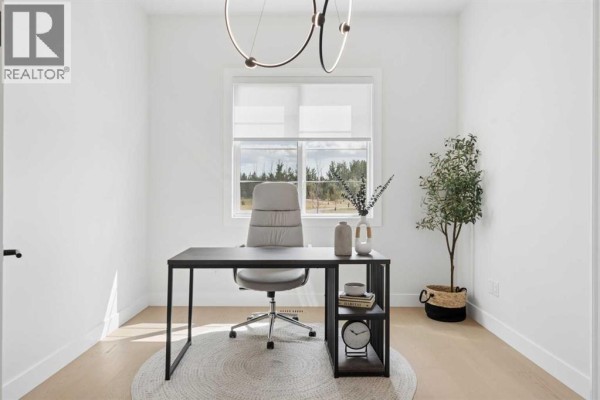 Home office with a desk, ergonomic chair, large window with blinds, and a modern light fixture. - 507 Waterford Rise, Chestermere
