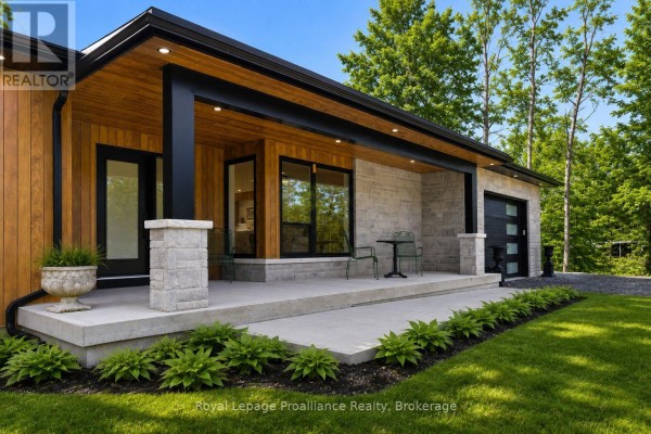 Front view of the house with a gravel driveway and black garage door. - 5070 County Rd 25, Trent Hills