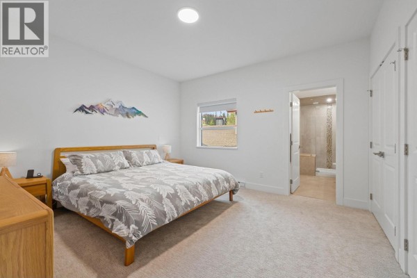 Bedroom with a king-sized bed, nightstands, and a view of the outdoors. - 5075 Snowbird Way Unit# 8e, Big White