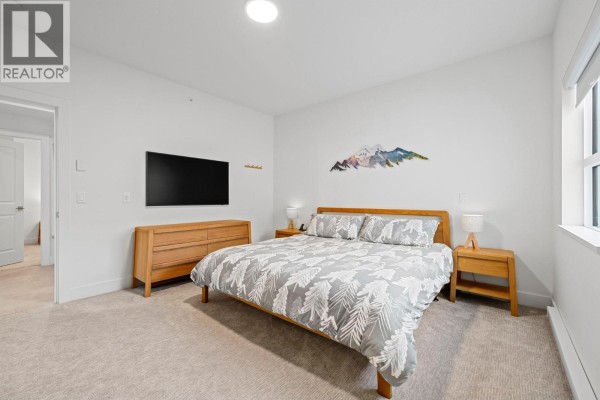 Bedroom with a king bed, dresser, nightstands, and a wall-mounted television. - 5075 Snowbird Way Unit# 8e, Big White