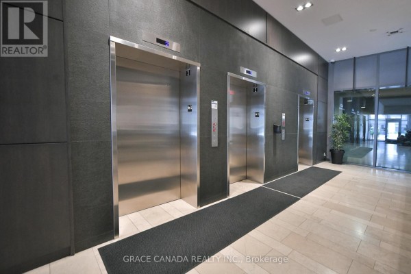 Elevator lobby with three stainless steel elevators and dark grey wall panels. - 508 - 1940 Ironstone Drive, Burlington
