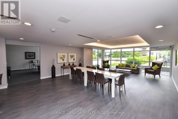 Amenity room with a long dining table, chairs, sofas, and large windows. - 508 - 1940 Ironstone Drive, Burlington