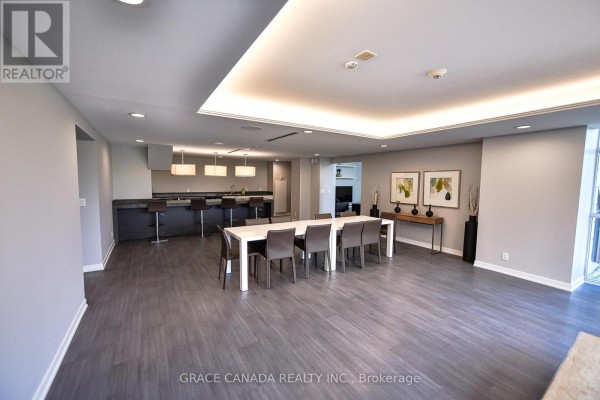 Amenity room with a dining table, chairs, and a modern kitchen island with bar stools. - 508 - 1940 Ironstone Drive, Burlington