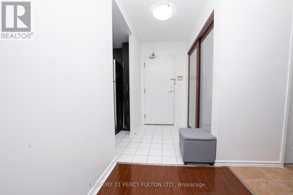 Apartment entrance hallway with white walls, tiled floor, and wooden closet doors. - 508 - 325 Webb Drive, Mississauga