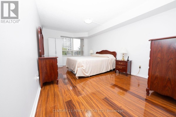 Bedroom with a king-size bed, wooden furniture, and polished wooden floors. - 508 - 325 Webb Drive, Mississauga