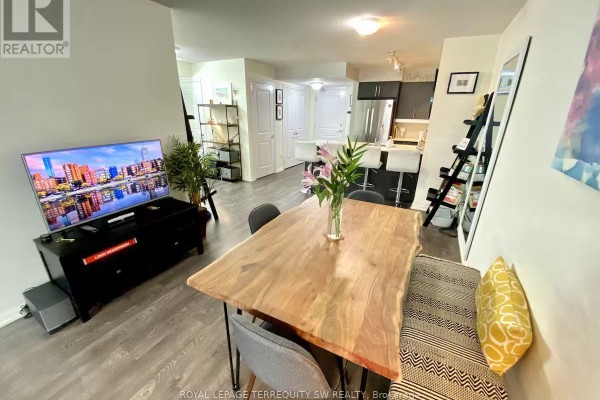 Open concept living and dining area with wood dining table and television. - 508 - 65 East Liberty Street, Toronto