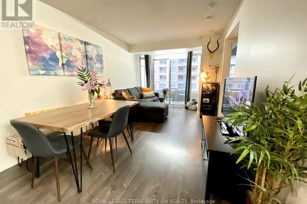 Living room with sectional sofa, dining area, and balcony with city views. - 508 - 65 East Liberty Street, Toronto