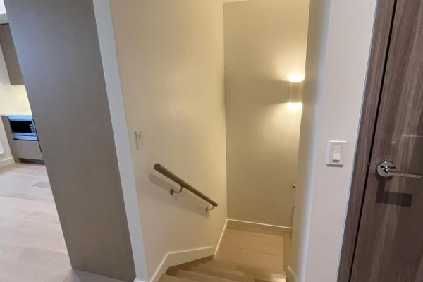 Staircase with wood banister and light wood treads leading down. - 508 - 95 Mcmahon Drive, Toronto