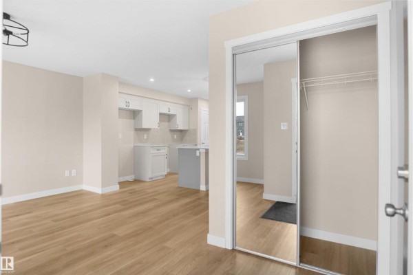 Entryway leading to open kitchen with light-colored cabinetry and laminate flooring - 508 176 Av Ne, Edmonton