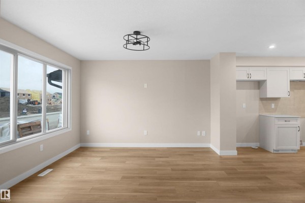 Living room with large window, neutral walls, and adjacent kitchen area - 508 176 Av Ne, Edmonton