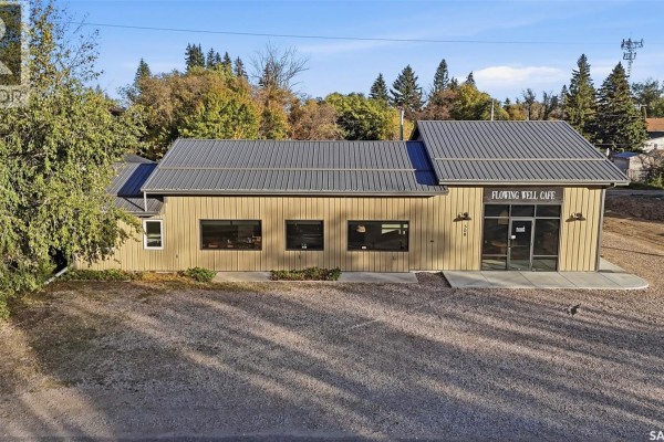Side view of a tan metal-clad commercial building with a grey metal roof and black-framed windows. - 508 Railway Street E, Hepburn