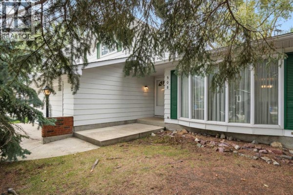 Front entrance of the house with a concrete walkway, large bay windows, and landscaping. - 508 Willow Brook Drive Se, Calgary