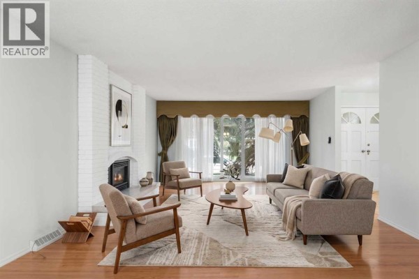 Living room with mid-century modern furniture, a white brick fireplace, and hardwood floors. - 508 Willow Brook Drive Se, Calgary