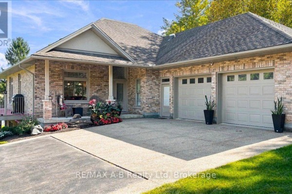 Close-up of the brick house exterior showing a double garage and covered entryway. - 5083 Perth 107 Road, Perth East