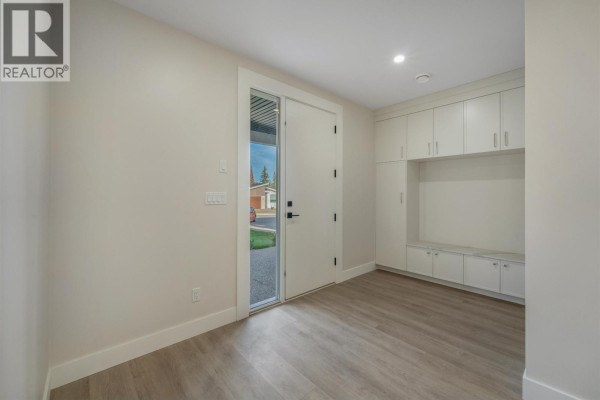 Primary bedroom with wood floors, beige walls, and an ensuite bathroom entrance. - 5089 Headlands Heights, Prince George