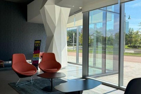 Apartment building lobby seating area with two orange chairs and black coffee tables. - 508b - 8 Rouge Valley Drive, Markham
