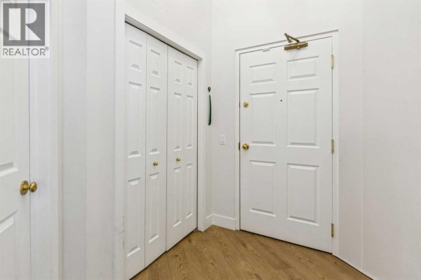 Apartment entryway with white bi-fold doors, a white panel door, and light wood laminate flooring. - 509, 923 15 Avenue Sw, Calgary