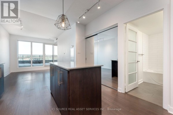 View of the kitchen and main living area from across the room, featuring a large mirrored closet. - 509 - 1169 Queen Street W, Toronto