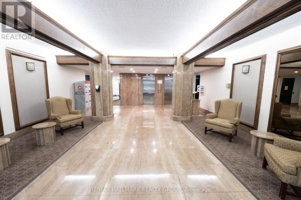 Building lobby with marble floors, beige wingback chairs, and elevators. - 509 - 2019 Carling Avenue, Ottawa