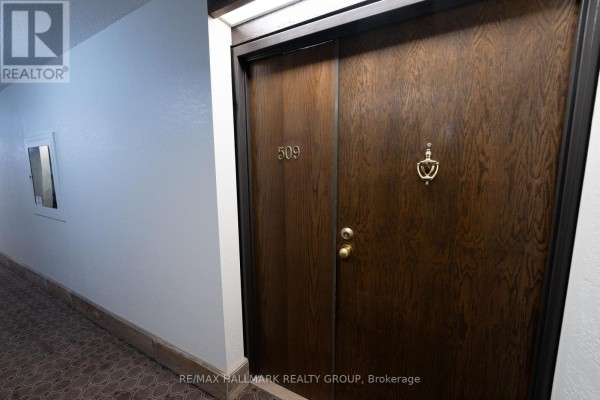 Apartment 509 wooden front door with brass knocker and peephole. - 509 - 2019 Carling Avenue, Ottawa