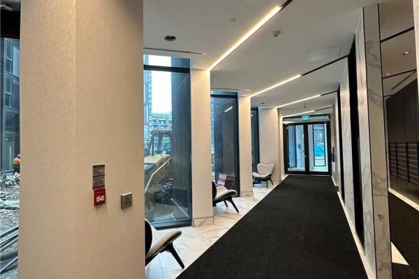 Interior hallway of the 30 Tretti Way building with dark carpet, marble accents, and seating. - 509 - 30 Tretti Way, Toronto