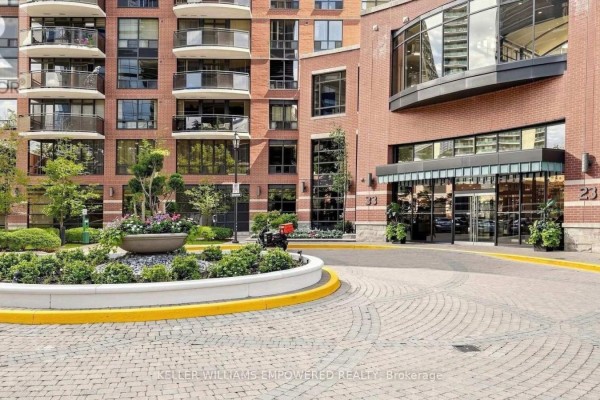 Driveway entrance to a brick condo building with landscaping and a circular planter. - 509 - 33 Sheppard Avenue E, Toronto