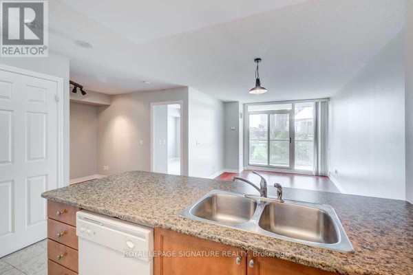 Kitchen island with a double sink and dishwasher overlooks living area with hardwood floors. - 509 - 51 Lower Simcoe Street, Toronto