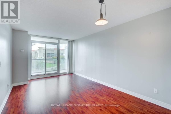 Empty living room with hardwood floors, gray walls, and a large sliding glass door. - 509 - 51 Lower Simcoe Street, Toronto