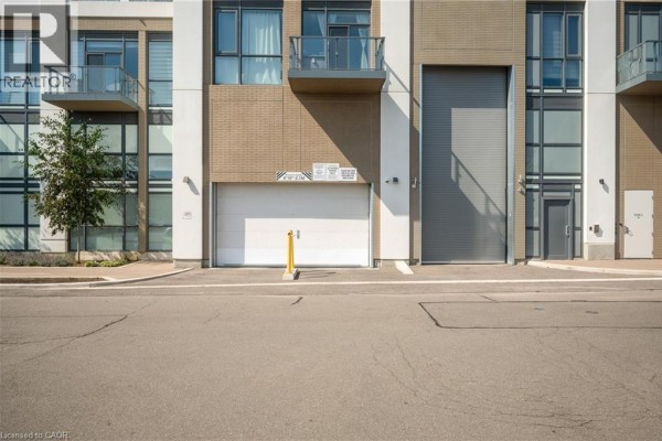 Close-up view of the ground level of the apartment building, showing a garage door and entrance. - 509 Dundas Street W Unit# 305, Oakville