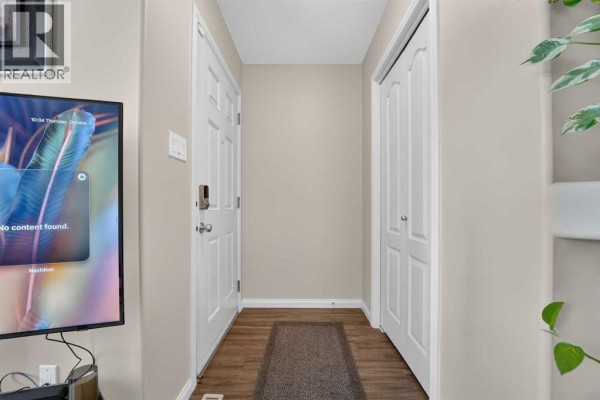 Interior entryway with a white door, closet, and television on a stand. - 509 Gateway Crescent S, Lethbridge
