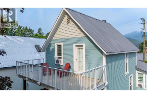 View of the upstairs balcony on the blue house with two red chairs and a metal railing. - 509 Mackenzie Avenue, Revelstoke