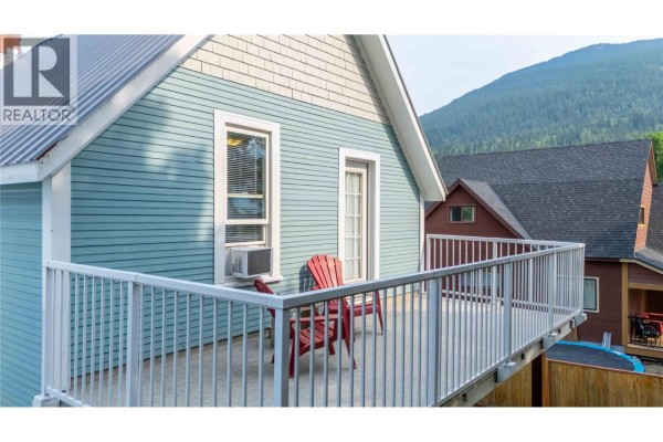 Close-up of the upstairs balcony on the blue house with red chairs and a view of Revelstoke mountains. - 509 Mackenzie Avenue, Revelstoke