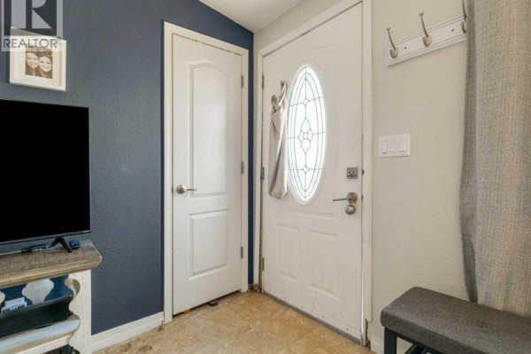 Interior entryway with a white front door with an oval glass insert and two interior doors. - 509 Station Street, Coaldale