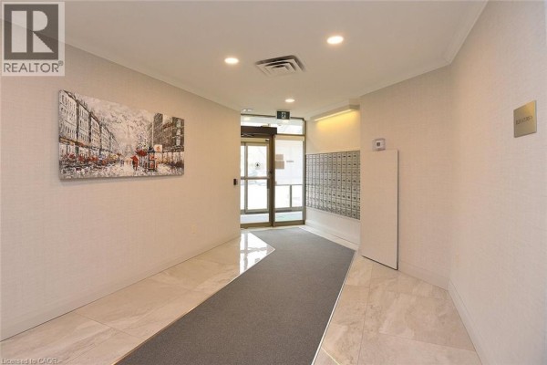 Building entrance with mailboxes, glass doors, and artwork. - 5090 Pinedale Avenue Unit# 501, Burlington