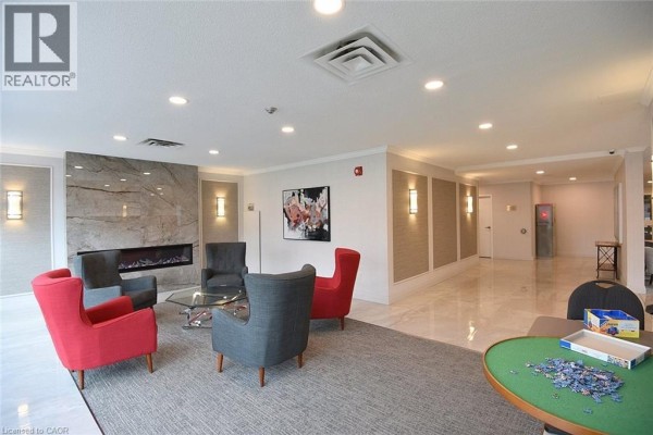 Communal lounge area with a fireplace, seating, and a puzzle table. - 5090 Pinedale Avenue Unit# 501, Burlington