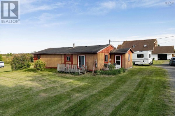Exterior view of a long, single-story house with a wooden deck and grassy yard. - 5096 Highway 366, Lorneville